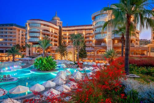 a hotel with a swimming pool in front of a building at Kirman Arycanda De Luxe in Okurcalar