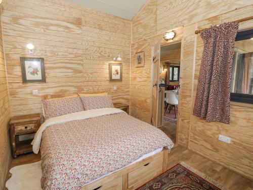 a bedroom with a bed in a room with wooden walls at Willow in Rugby