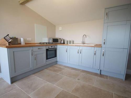 a kitchen with white cabinets and a tile floor at Stunning cottage close to city centre - Pass the Keys in Bath