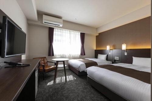 大阪市にあるホテルウィングインターナショナルプレミアム大阪新世界のベッド2台、薄型テレビが備わるホテルルームです。
