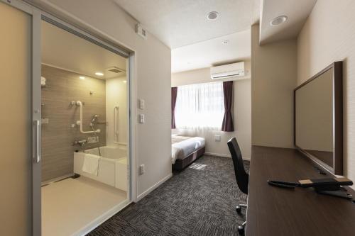 a hotel room with a desk and a sliding glass door at Hotel Wing International Premium Osaka-Shinsekai in Osaka