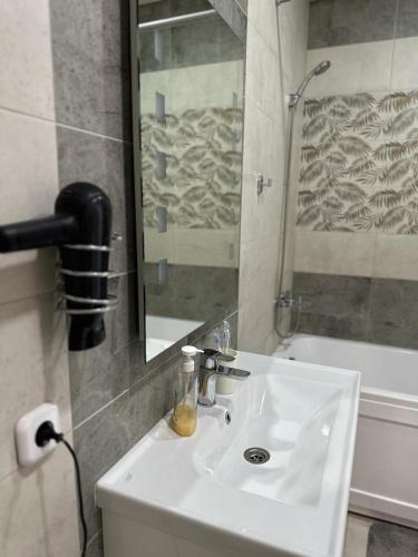 a bathroom with a sink and a mirror and a tub at Новая современная квартира в центре города in Kostanay