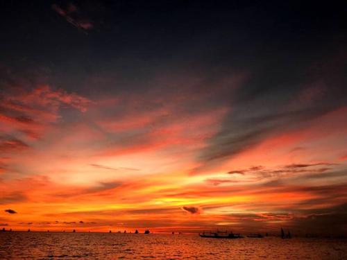 een zonsondergang over de oceaan met mensen op het strand bij Tara staycation unit in Boracay