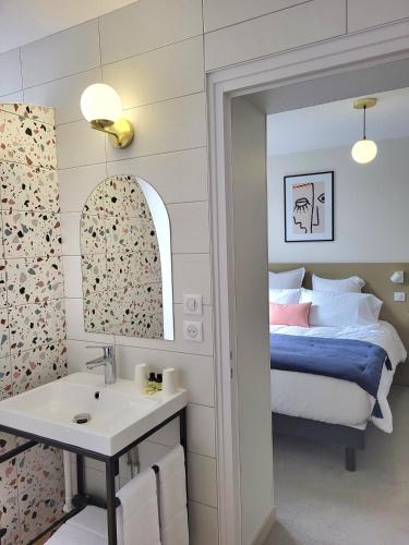 a bedroom with a bed and a sink and a mirror at Mage hôtels - HÔTEL LA GRENETTE in Roanne