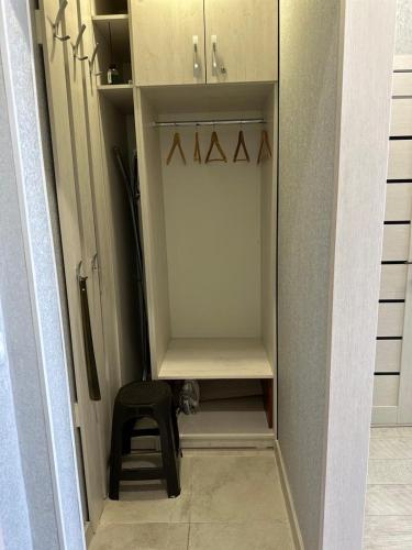 a walk in closet with a chair and a stool at Новая современная квартира в центре города in Kostanay