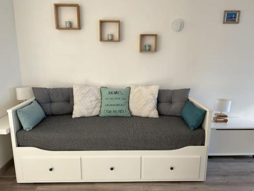 a couch with pillows on it in a room at Les Bains Studio Vue Mer in Pléneuf-Val-André