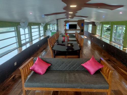 a couch with pink pillows sitting in a dining room at Beach Paradise Day Cruise Houseboat in Alleppey