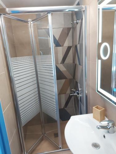 a shower with a glass door next to a sink at Mpitzarakis Studio On the Beach in Agia Pelagia