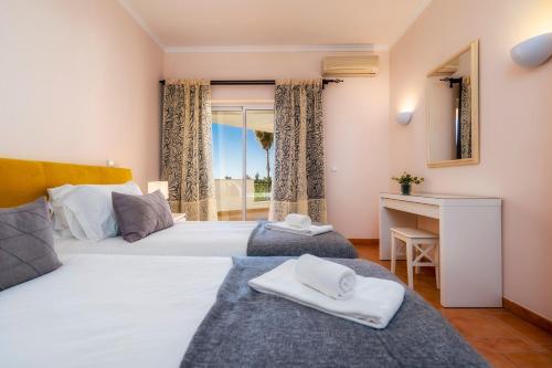 a bedroom with two beds and a desk and a window at Colina Verde Resort in Moncarapacho