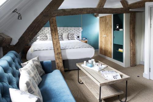 1 dormitorio con 1 cama y 1 sofá azul en The Old Stocks Inn en Stow on the Wold