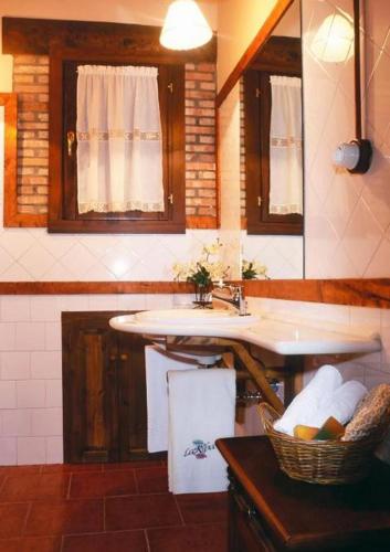 a bathroom with a sink and a basket of towels at Casa Rural La Riba in Sames