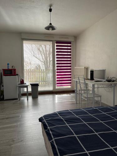 salon z łóżkiem i stołem z krzesłami w obiekcie Logement type studio 1 piece proche zénith w Strasburgu