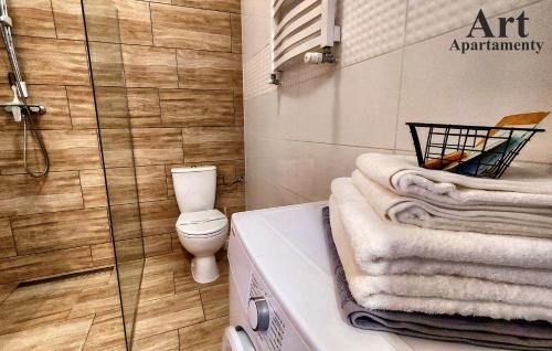 y baño con aseo y ducha con toallas. en Art Apartamenty 2, en Kalisz