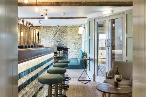 a bar with green stools and a stone wall at The Old Stocks Inn in Stow on the Wold