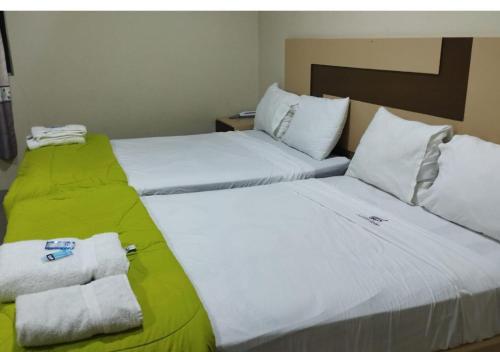 two beds in a hotel room with towels at Hotel La Suite de Angelique Huacho in Huacho
