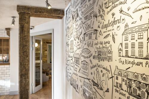 een muur bedekt met tekeningen van steden en gebouwen bij The Old Stocks Inn in Stow on the Wold