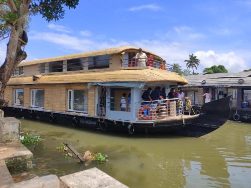 a house boat on the water with people on the deck at Beach Paradise Day Cruise Houseboat in Alleppey