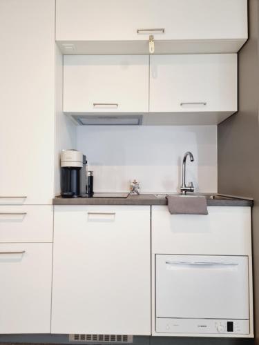 una cocina con armarios blancos y fregadero en SKY HOME, en Frankfurt