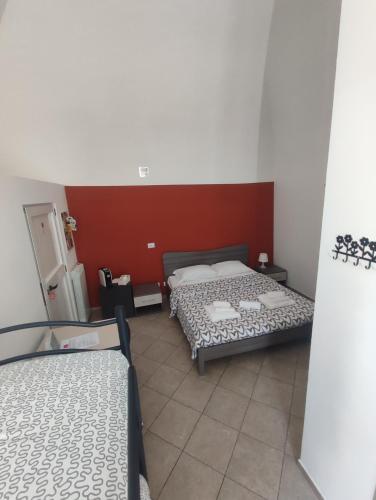a bedroom with two beds and a red wall at Le case di Marga in Santeramo in Colle