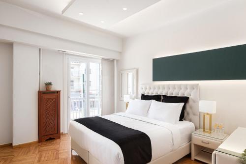 a white bedroom with a large bed and a window at Acropolis Prestige Residence in Athens