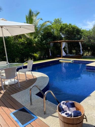a swimming pool with a table and chairs and an umbrella at Costa do Sauipe Casa dentro do complexo hoteleiro in Costa do Sauipe
