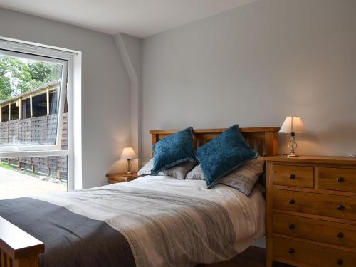 a bedroom with a bed with blue pillows and a window at Lords View in Ruckinge