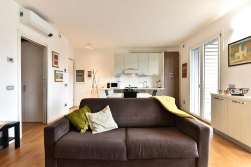 sala de estar con sofá marrón y cocina en CaseOspitali - Casa Kikka elegante appartamento con balcone in nuovo condominio, en Cernusco sul Naviglio