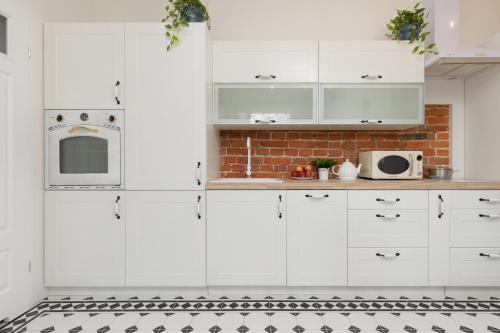 a kitchen with white cabinets and a black and white tile floor at Warsaw Pruszków Park View Comfortable Apartments by Renters in Pruszków