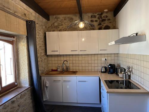 a kitchen with white cabinets and a sink at Studio de charme au coeur de Valréas in Valréas