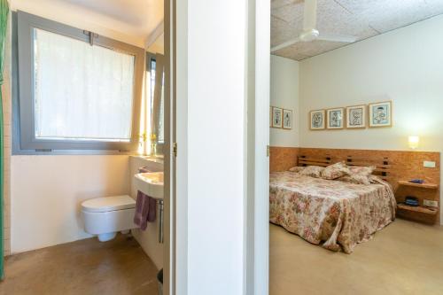 1 dormitorio con cama, lavabo y aseo en La casita del bosque, en Vilopríu