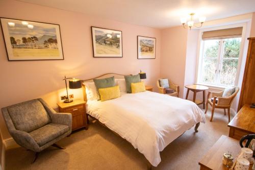 a bedroom with a bed and a chair and a window at Fairfield House and Gardens in Bowness-on-Windermere