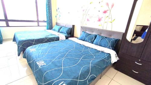 2 camas en una habitación con sábanas azules y espejo en Mevin Woodsbury Suite Butterworth Penang, en Butterworth