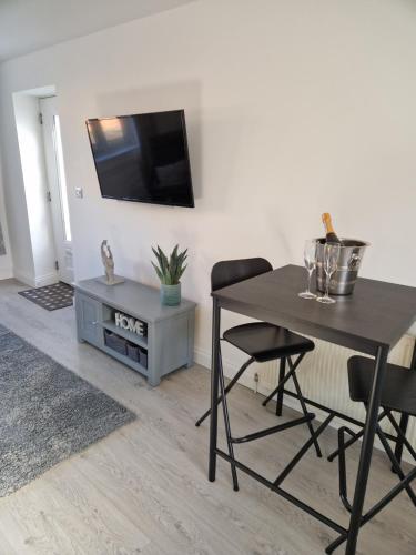 a dining room with a table and a tv on a wall at The Lodge, 9 Dene House in Gateshead