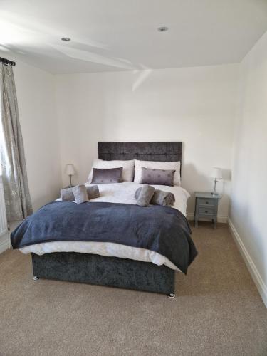 um quarto com uma cama grande num quarto branco em The Lodge, 9 Dene House em Gateshead