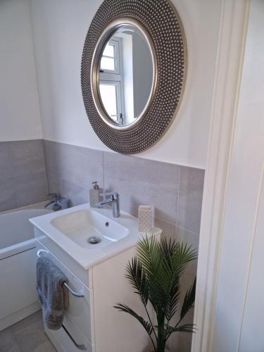 ein Bad mit einem Waschbecken und einem Spiegel in der Unterkunft The Lodge, 9 Dene House in Gateshead