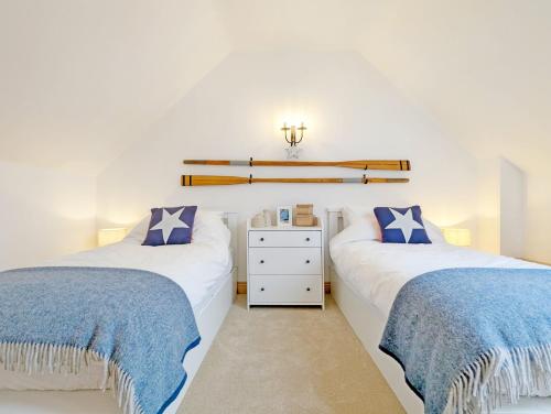 2 łóżka w sypialni z niebieską i białą pościelą w obiekcie Stable Cottage w mieście Woodmancote