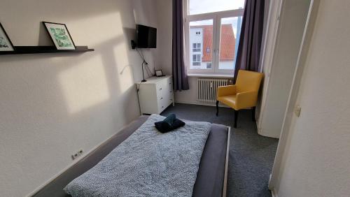 a bedroom with a bed and a yellow chair and a window at Gäste-Liesel Bad Pyrmont in Bad Pyrmont