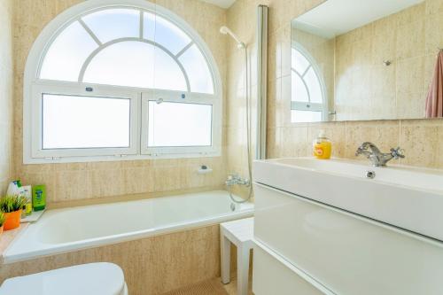 an arched window in a bathroom with a tub and a sink at Casa Laura in Puerto del Carmen