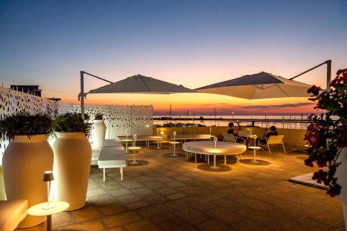 a patio with tables and chairs and umbrellas at sunset at Xilhotel in Gallipoli