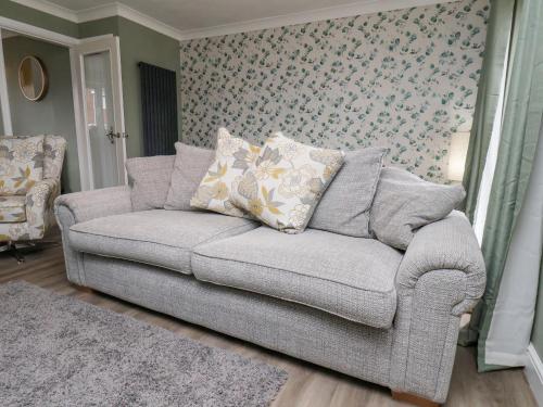 a gray couch in a living room with floral wallpaper at 22 Constable Road in Filey