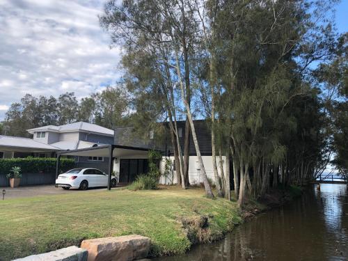 a house with a car parked next to a river at The COCO in The Entrance