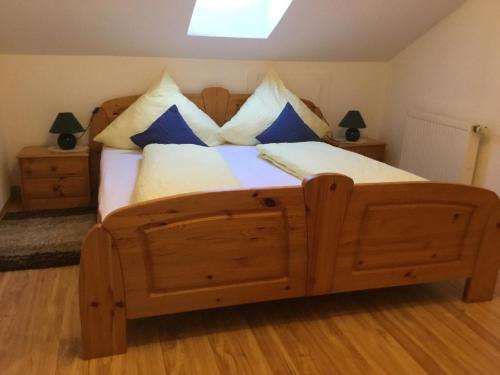 a bedroom with a wooden bed with blue and white pillows at Ferienwohnungen Schellein in Blaibach