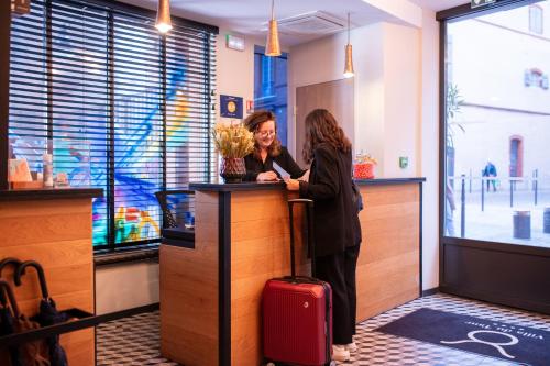 two women are standing at a counter in a store at Logis Hôtel Villa du Taur in Toulouse