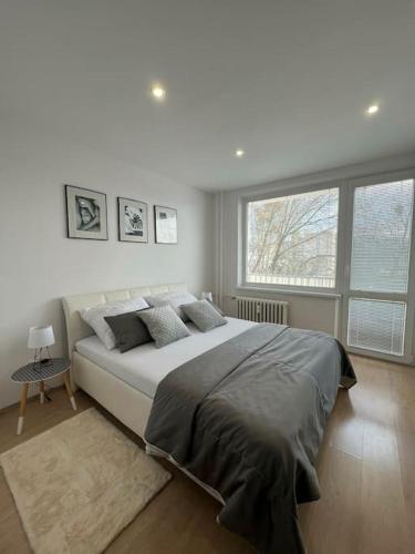 a white bedroom with a large bed and a window at Komfort byt s parking zadarmo in Košice