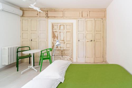 レッチェにあるKOLOR B&Bの緑のベッド、テーブル、椅子が備わる客室です。