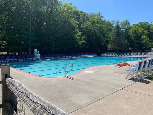 a large swimming pool with chairs and trees in the background at Stylish and Cozy Cabin, Walking Distance to Big Bass Lake in Gouldsboro