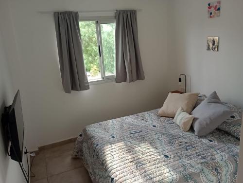 1 dormitorio con cama con almohadas y ventana en DEPARTAMENTOS LEMOS TRES en Mendoza