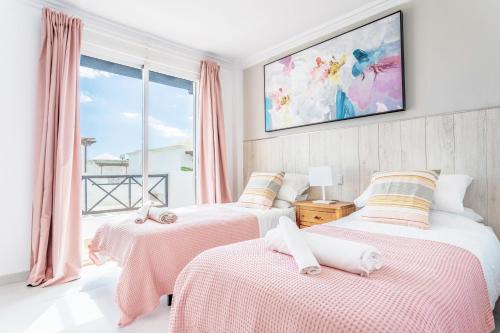 a bedroom with two beds with pink sheets and a window at Casa Laura in Puerto del Carmen