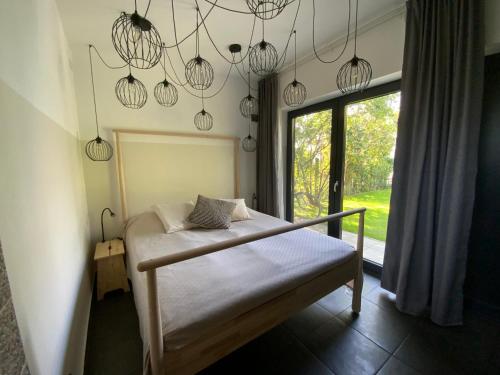 1 dormitorio con 1 cama con ventana y lámparas de araña en Kemény Klára Parti Háza en Zamárdi