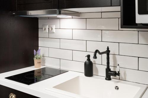 a kitchen sink with a black and white tiled wall at Acropolis Prestige Residence in Athens